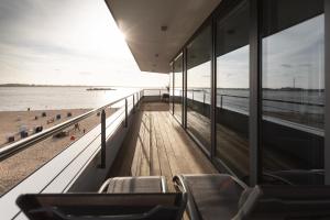 Blick auf den Strand von einem Gebäude mit Stühlen in der Unterkunft Bheaven I Penthouse Premium Apartment in Bremerhaven