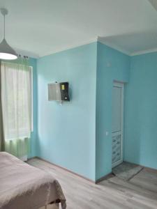 niebieski pokój z łóżkiem i oknem w obiekcie Nunu's Guesthouse w mieście Ckaltubo