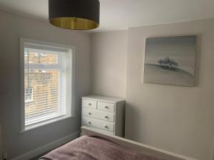 a bedroom with a bed and a dresser and a window at Tipsy Cottage Charming 2 bedroom home. in Burley in Wharfedale
