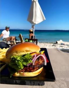 a hamburger on a plate on a table at the beach at Vasiliki see view apartments in Barbati