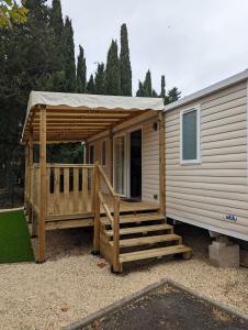 a mobile home with a porch and a deck at Mobil home 6/8personnes in Sérignan