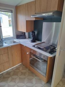 una pequeña cocina con fogones y fregadero en Mobil home 6/8personnes, en Sérignan