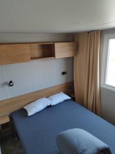 Un dormitorio con una cama azul y una ventana en Mobil home 6/8personnes en Sérignan