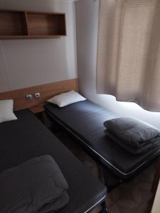 two beds in a small room with a window at Mobil home 6/8personnes in Sérignan