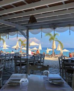 a restaurant on the beach with tables and chairs at Vasiliki see view apartments in Barbati