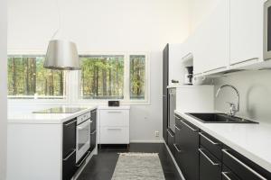 a white kitchen with black appliances and a window at Villa Tuomipakka in Kalajoki