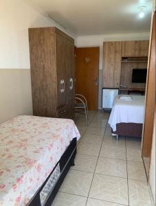 a bedroom with a bed and a tv and a room with a bed at HOTEL VITORIA REGIA in Engenheiro Beltrão