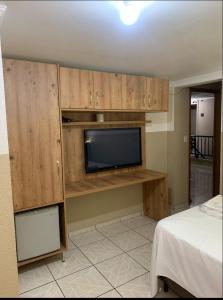 a living room with a tv and a room with a bed at HOTEL VITORIA REGIA in Engenheiro Beltrão