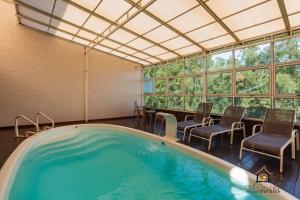 bañera de hidromasaje en una habitación con sillas y ventanas en Hotel Morada Del Este en Canoas