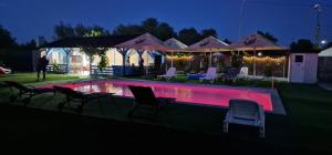 a swimming pool with chairs and umbrellas at night at Splendoarea Deltei in Maliuc