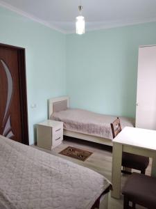 een slaapkamer met 2 bedden, een tafel en een bureau bij Nunu's Guesthouse in Tskaltubo