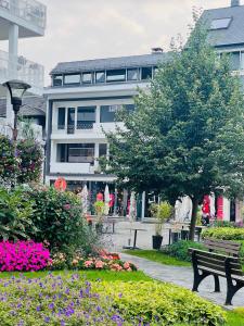 un parc avec un banc et des fleurs devant un bâtiment dans l'établissement NEOZONE Neostudio Malmedy, à Malmedy