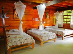 3 camas en una habitación con paredes de madera en Madera Labrada Lodge Ecologico, en Tarapoto