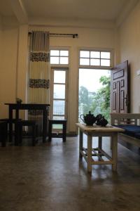 a room with a table and a bench and windows at simply heaven suriyakanda in Suriyakanda