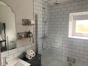 y baño con bañera, lavamanos y ducha. en Tipsy Cottage Charming 2 bedroom home., en Burley in Wharfedale