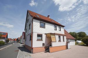 a white house with a red roof on a street at Rhöner Heim in Kaltennordheim