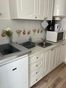 uma cozinha com armários brancos, um lavatório e um micro-ondas em Mikszáth Apartman em Balatonfüred