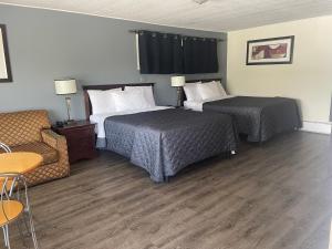 a hotel room with two beds and a chair at Nites Inn Motel in Cornwall