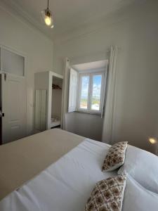 1 dormitorio blanco con 1 cama blanca grande y 2 almohadas en Guesthouse Casa Felicia, en Montes de Alvor