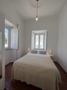 1 dormitorio blanco con 1 cama grande y 2 ventanas en Guesthouse Casa Felicia, en Montes de Alvor