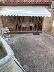 a patio with a table and a white umbrella at VILLA GIULIANA stanze con bagno interno in Villa a 350 mt spiaggia libera Lido delle Sirene in Anzio