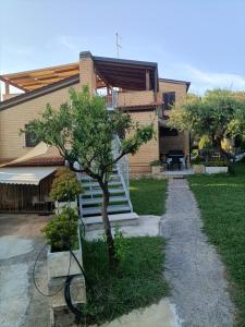 uma pequena árvore em frente a uma casa em VILLA GIULIANA stanze con bagno interno in Villa a 350 mt spiaggia libera Lido delle Sirene em Anzio