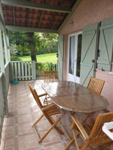 ein Holztisch und Stühle auf einer Terrasse in der Unterkunft Le Clos des Mimosas in Saint-Andéol-de-Vals