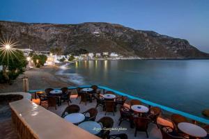 a group of tables and chairs next to a body of water at Irene's studios in Panormos Kalymnos