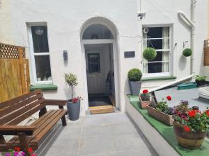 a porch with a bench and flowers in front of a house at The Collingdale Guest House in Ilfracombe