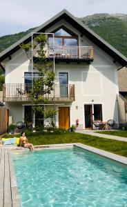 un homme assis dans une piscine en face d'une maison dans l'établissement Emerald Valley Apartments, à Bovec
