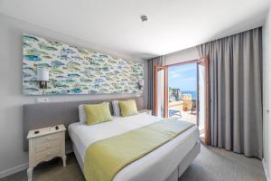 a hotel room with a bed and a large window at Castelo Guest House in Carvoeiro