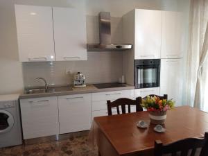 a kitchen with white cabinets and a wooden table at Eva Casa Vacanza in Felline