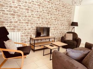 a living room with a tv and a brick wall at Sur le chemin de la plage in Cherbourg en Cotentin