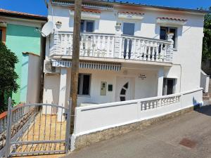 Casa bianca con balcone su una strada di Apartmani Ana-Lora a Lopar