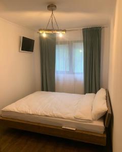 a bed in a bedroom with a window with green curtains at Pensiunea Lili’s House in Buchin