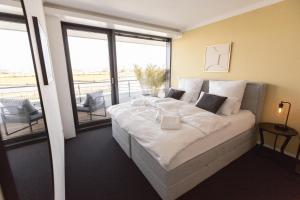 a bedroom with a large white bed and a balcony at Bheaven I Marina Premium Apartment in Bremerhaven