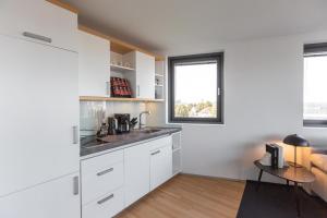 a kitchen with white cabinets and a table at Bheaven I Marina Premium Apartment in Bremerhaven