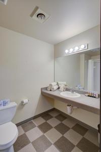 a bathroom with a toilet and a sink and a mirror at Pacific Sunrise Inn & Suites in Ocean Shores