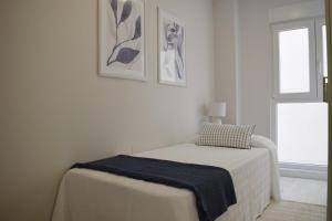 a white bedroom with a bed and a window at JOMAR Apartamento en Coruña in A Coruña
