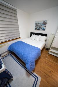 a bedroom with a bed with a blue blanket at Apartman Daris in Sarajevo +4 photos