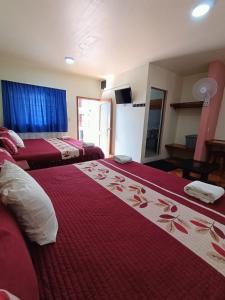 una camera d'albergo con due letti con lenzuola rosse e fiori di Hotel John & Rose a Comitán de Domínguez