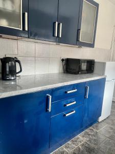 eine Küchentheke mit blauen Schränken und einer Mikrowelle in der Unterkunft Spacious 4 Bed Property - Sleeps 8 in Gateshead in Felling