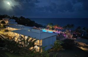 a resort with a pool and the ocean at night at Un petit joyau in Le Diamant