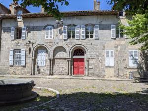 - un vieux bâtiment en pierre avec une porte rouge dans l'établissement À l'ombre de l'abbatiale, 90 m² rénovés 3 chambres, à Aurillac