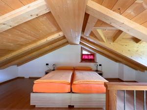 una camera da letto con letto arancione in mansarda di Chalet I Clus a Livigno