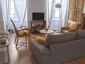 - un salon avec un canapé, des chaises et une télévision dans l'établissement À l'ombre de l'abbatiale, 90 m² rénovés 3 chambres, à Aurillac