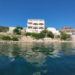 a building on the shore of a body of water at Apartments Radic in Rogoznica