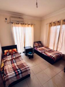 two beds sitting in a room with windows at DeadSea Accommodation with AC in Sowayma