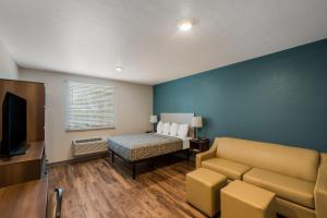 Habitación con sofá, cama y TV. en WoodSpring Suites West Palm Beach, en West Palm Beach