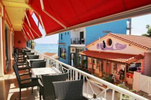 a balcony with tables and chairs and the ocean at Brati II Beach Hotel in Arkoudi